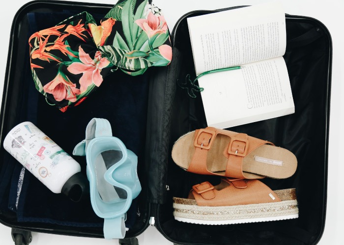 maleta para verano con sandalias de plataforma marrones bañador tropical y gafas de snorkel