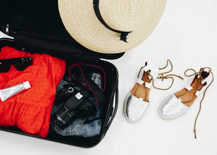 maleta para verano con vestido rojo y gafas de sol combinado con espartos de cordones plateada